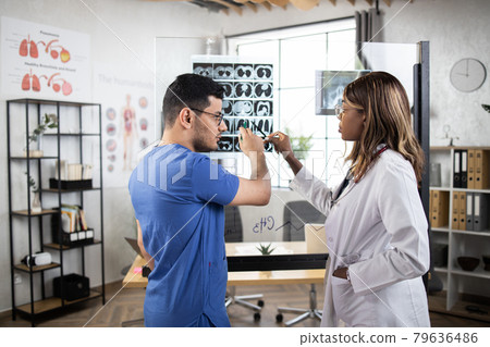 Female and male hospital doctors attentively checking patient mri scan, regular examination Female and male hospital doctors attentively checking patient mri scan, regular examination 79636486