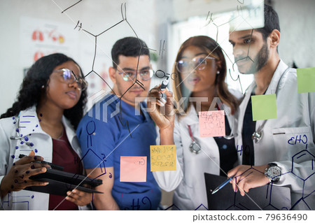 Male Doctor with scientist glasses writing something with marker on glass, wall Male Doctor with scientist glasses writing something with marker on glass, wall 79636490