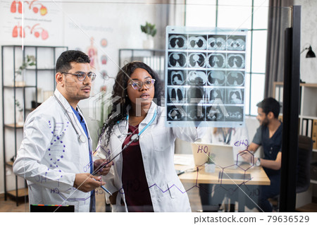 International doctors discussing results of x ray scan International doctors discussing results of x ray scan 79636529