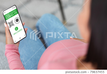 Pregnant woman using smartphone with digital health passport 79637455