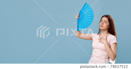 Sweaty beautiful lady with closed eyes cooling with hand fan Sweaty beautiful lady with closed eyes cooling with hand fan 79637522