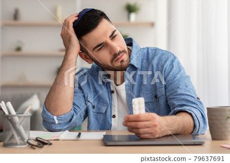 Young man suffering from illness, holding tablets 79637691