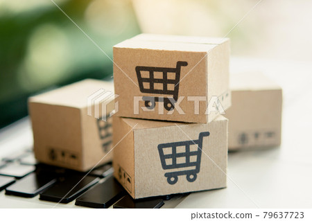 Shopping online. Cardboard box with a shopping cart logo on laptop keyboard. Shopping service on The online web. offers home delivery. copy space. 79637723