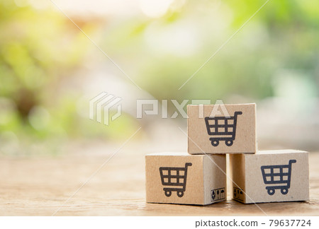 Online shopping - Paper cartons or parcel with a shopping cart logo and credit on wood table top with copy space. Shopping service on The online web and offers home delivery. 79637724