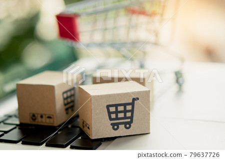 Shopping online. Cardboard box with a shopping cart logo on laptop keyboard. Shopping service on The online web. offers home delivery. copy space. Shopping online. Cardboard box with a shopping cart logo on laptop keyboard. Shopping service on The online web. offers home delivery. copy space. 79637726