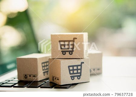 Shopping online. Cardboard box with a shopping cart logo on laptop keyboard. Shopping service on The online web. offers home delivery. copy space. Shopping online. Cardboard box with a shopping cart logo on laptop keyboard. Shopping service on The online web. offers home delivery. copy space. 79637728