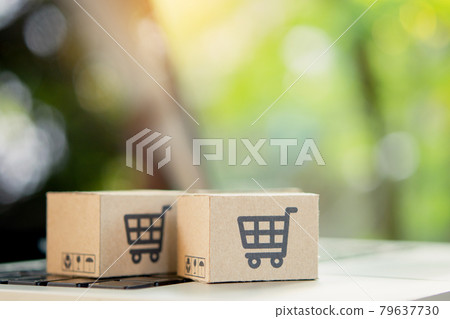 Shopping online. Cardboard box with a shopping cart logo on laptop keyboard. Shopping service on The online web. offers home delivery. copy space. Shopping online. Cardboard box with a shopping cart logo on laptop keyboard. Shopping service on The online web. offers home delivery. copy space. 79637730