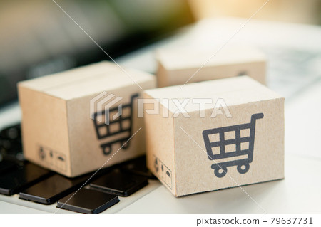 Shopping online. Cardboard box with a shopping cart logo on laptop keyboard. Shopping service on The online web. offers home delivery. copy space. Shopping online. Cardboard box with a shopping cart logo on laptop keyboard. Shopping service on The online web. offers home delivery. copy space. 79637731
