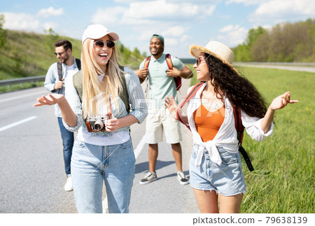 Group of multinational millennial friends walking along highway, chatting to each other, laughing, having fun 79638139