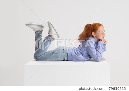 Side view. Portrait of smiling red-headed girl in casual clothes isolated on white studio background. Happy childhood concept. Sunny child. Looks happy, delighted Side view. Portrait of smiling red-headed girl in casual clothes isolated on white studio background. Happy childhood concept. Sunny child. Looks happy, delighted 79639313