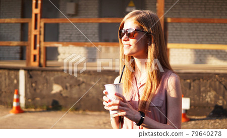 Young woman with a cup of lemonade outside. Sunny day and urban food court Young woman with a cup of lemonade outside. Sunny day and urban food court 79640278
