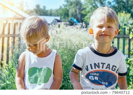 Upset brothers sitting on bench in summerhouse sunny yard Upset brothers sitting on bench in summerhouse sunny yard 79640712
