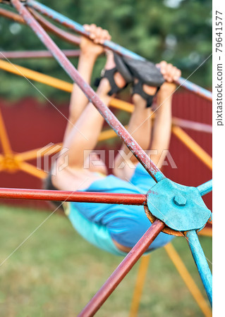 Little boy hangs on colorful climbing play set in city park Little boy hangs on colorful climbing play set in city park 79641577