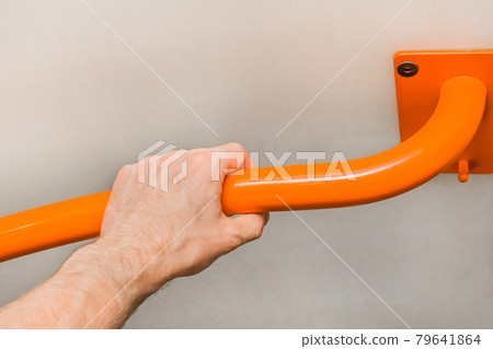 Man's hand holding a metal handrail in the toilet 79641864