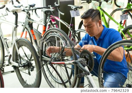 Salesman Adjusting Chain of Bicycle 79642329