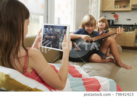 Girl Filming Brother Playing Guitar Girl Filming Brother Playing Guitar 79642423