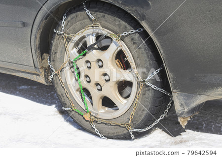 Close-up of snow chains on tires on a winter road Close-up of snow chains on tires on a winter road 79642594