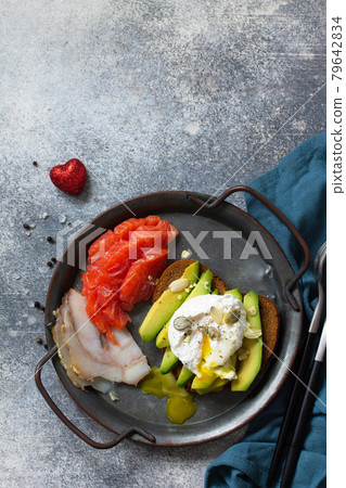 Valentine's day breakfast. Boiled egg sandwich with avocado, coffee, salmon and smoked salmon on a stone concrete tabletop. Top view flat lay background. Copy space. Valentine's day breakfast. Boiled egg sandwich with avocado, coffee, salmon and smoked salmon on a stone concrete tabletop. Top view flat lay background. Copy space. 79642834