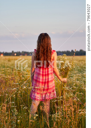 Vertical shot back view young girl with flowers on the field. Vertical shot back view young girl with flowers on the field. 79643027