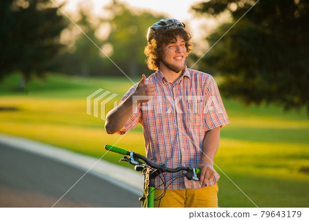 Male person with bicycle gesturing thumb up. 79643179