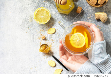 Woman holds a hot cup of ginger tea. Top view flat lay. Free space for your text. Woman holds a hot cup of ginger tea. Top view flat lay. Free space for your text. 79643247