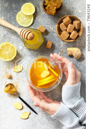Woman holds a hot cup of ginger tea. Top view flat lay. 79643248