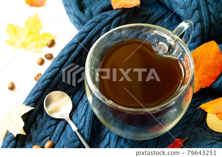 Cup of coffee with a heart shape on a warm knitted plaid background with autumn leaves. Cup of coffee with a heart shape on a warm knitted plaid background with autumn leaves. 79643251