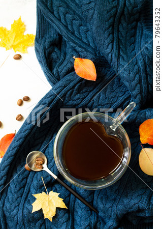 Cup of coffee with a heart shape on a warm knitted plaid background with autumn leaves. Top view flat lay background. Cup of coffee with a heart shape on a warm knitted plaid background with autumn leaves. Top view flat lay background. 79643252
