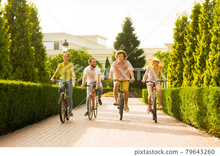 Happy young bike riders in summer park. Happy young bike riders in summer park. 79643260