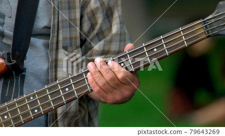 Male fingers holding guitar outdoors. Male fingers holding guitar outdoors. 79643269