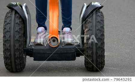 Girl standing on two wheeled segway. 79643291