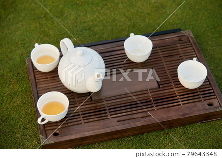 White tea pot and tea cups. 79643348