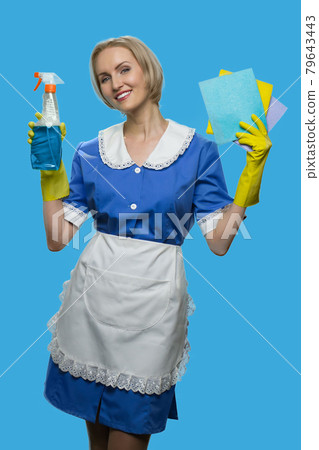 Cheerful maid in uniform holding rags and detergent. 79643443