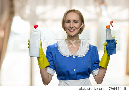 Beautiful house maid holding cleaning supplies and looking at camera. Beautiful house maid holding cleaning supplies and looking at camera. 79643446