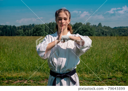 teenage girl training karate kata outdoors, greetings oss 79643899