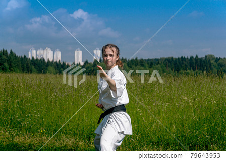 teenage girl training karate kata outdoors, performs soto uke or outside block teenage girl training karate kata outdoors, performs soto uke or outside block 79643953