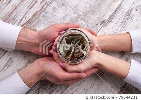 Top view hands holding family savings jar. 79644231