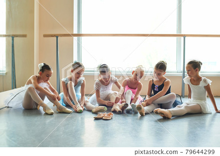 Six beautiful ballerinas putting on slippers. 79644299