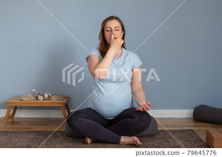 Pregnant woman practices yoga at home breathing nadi shodhana pranayma 79645776