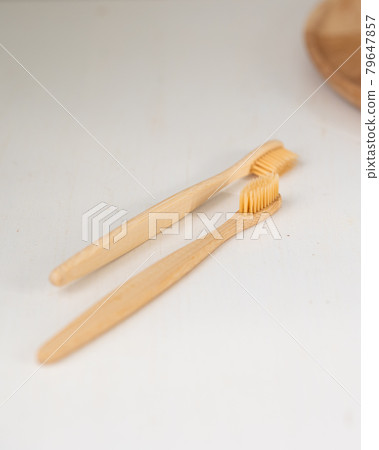 daily human hygiene, cotton swabs and cotton pads, a woman's hand holding bamboo toothbrushes on a light background in a glass or against the background of a wooden tray daily human hygiene, cotton swabs and cotton pads, a woman's hand holding bamboo toothbrushes on a light background in a glass or against the background of a wooden tray 79647857