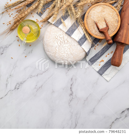 Fresh homemade yeast dough resting on marble table with ears of wheat and rolling pin. Fresh homemade yeast dough resting on marble table with ears of wheat and rolling pin. 79648231
