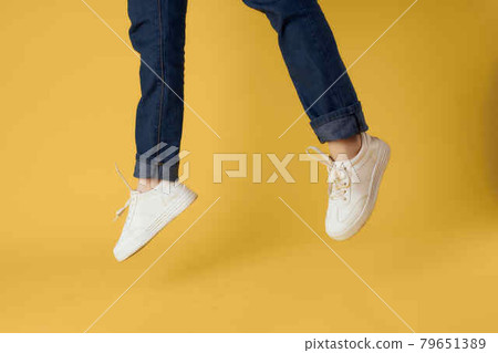 female feet cropped view white shoes fashion yellow background 79651389