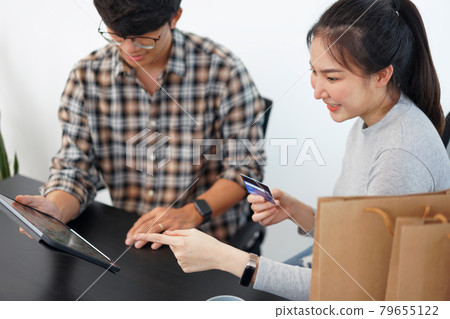 Shopping online concept a lovely couple adding credit card information to use in online financial transaction Shopping online concept a lovely couple adding credit card information to use in online financial transaction 79655122