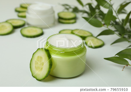 Jars with cosmetic cream, cucumber slices and branch on white table 79655910