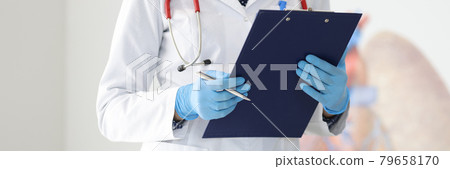 Doctor's hands in protective gloves hold clipboard and pen 79658170