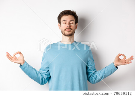 Young man trying to relax in meditation, standing calm with stretch out hands in zen mudra gesture, practice yoga on white background 79659112
