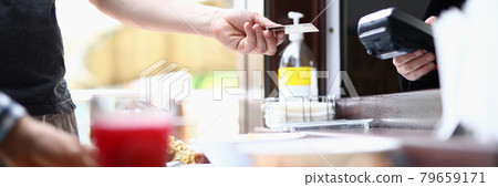 Man's hand holds out contactless bank card to cashier to pay for lunch Man's hand holds out contactless bank card to cashier to pay for lunch 79659171
