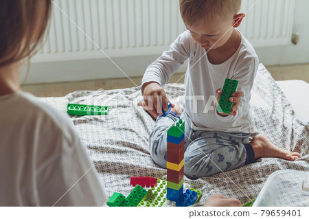 Mom and kid play together in the bedroom with plastic blocks Mom and kid play together in the bedroom with plastic blocks 79659401