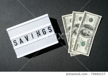 Lightbox board with word SAVINGS in black letters around US dollar banknotes. Money, Business, finance, investment, saving 79660257