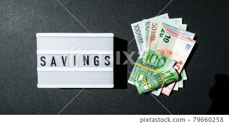 Lightbox board with word SAVINGS in black letters around Euro banknotes. Money, Business, finance, investment, saving 79660258